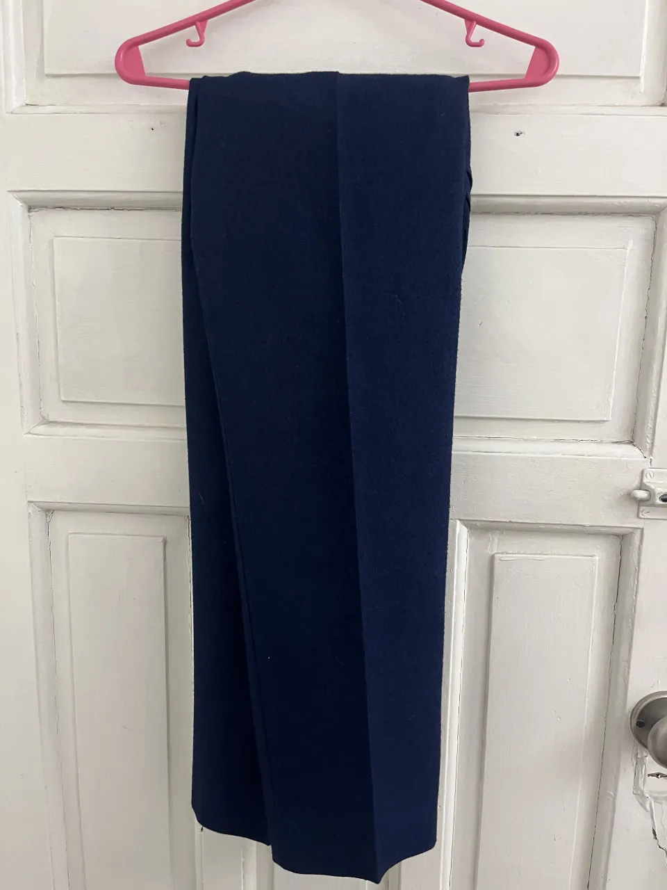 Conjunto de pantalón y blazer azul marino. El pantalón tiene pinzas y cierre con botón. El blazer tiene solapas y un bolsillo.