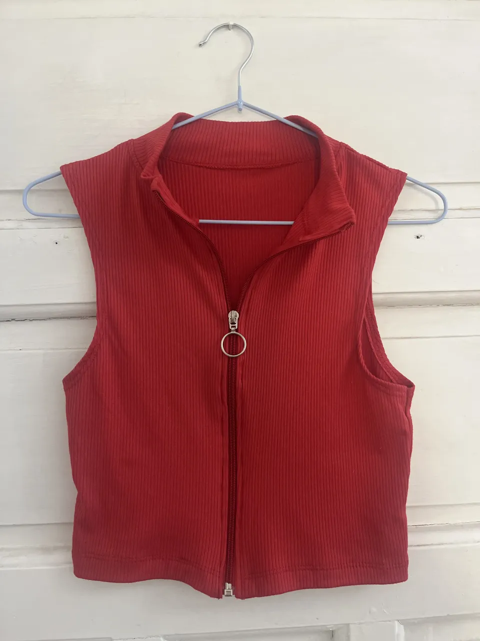Musculosa roja de tejido acanalado con cuello alto y cierre metálico con aro al frente.