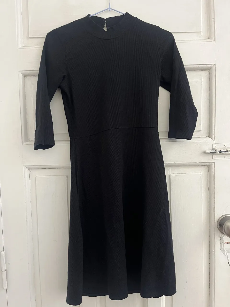 Vestido negro de manga 3/4 y cuello alto.