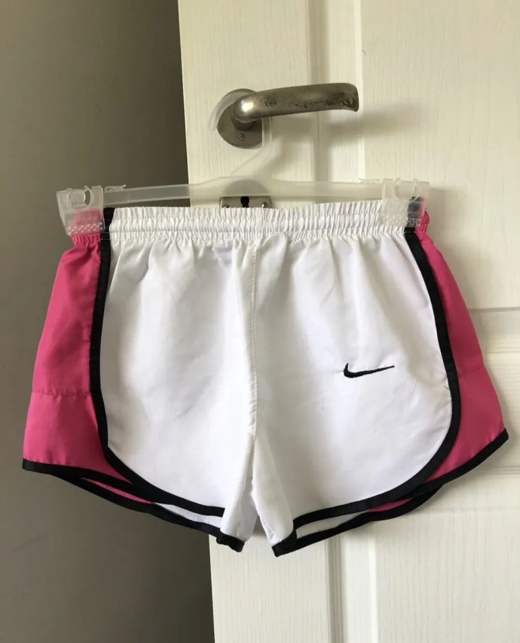 Shorts deportivos Nike blancos con detalles en rosa y negro. Ideales para running o entrenamiento.