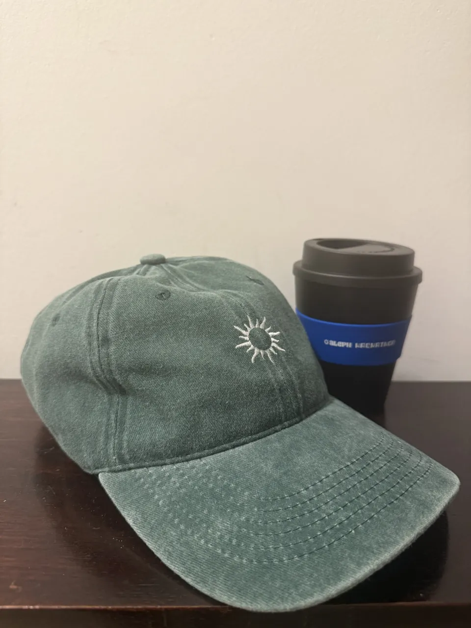 Gorra de color verde vintage con un bordado de sol en la parte frontal.