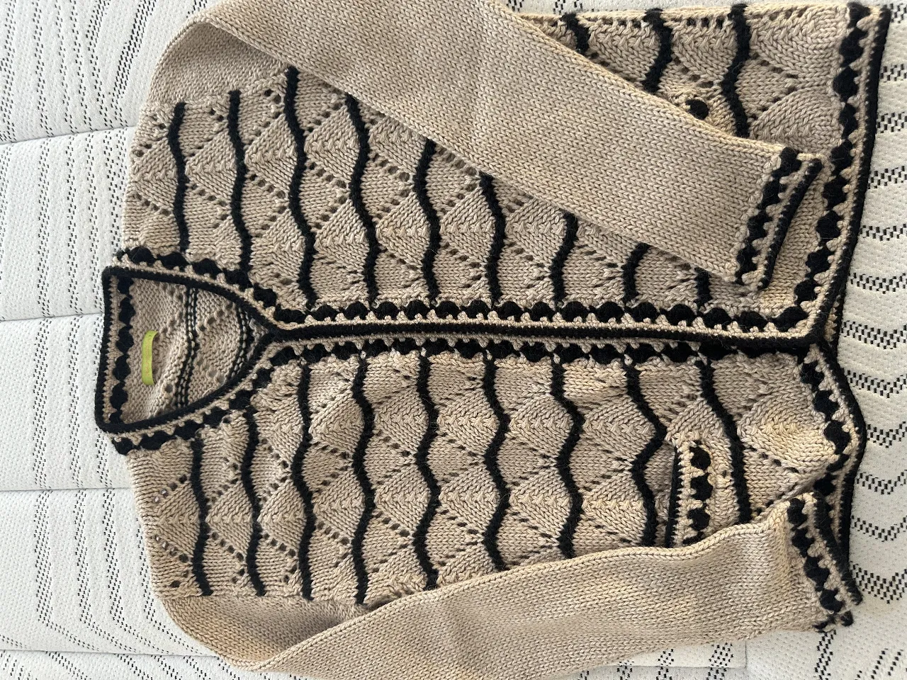 Cardigan tejido de punto, con diseño calado y detalles en negro. Ideal para un look casual y abrigado.