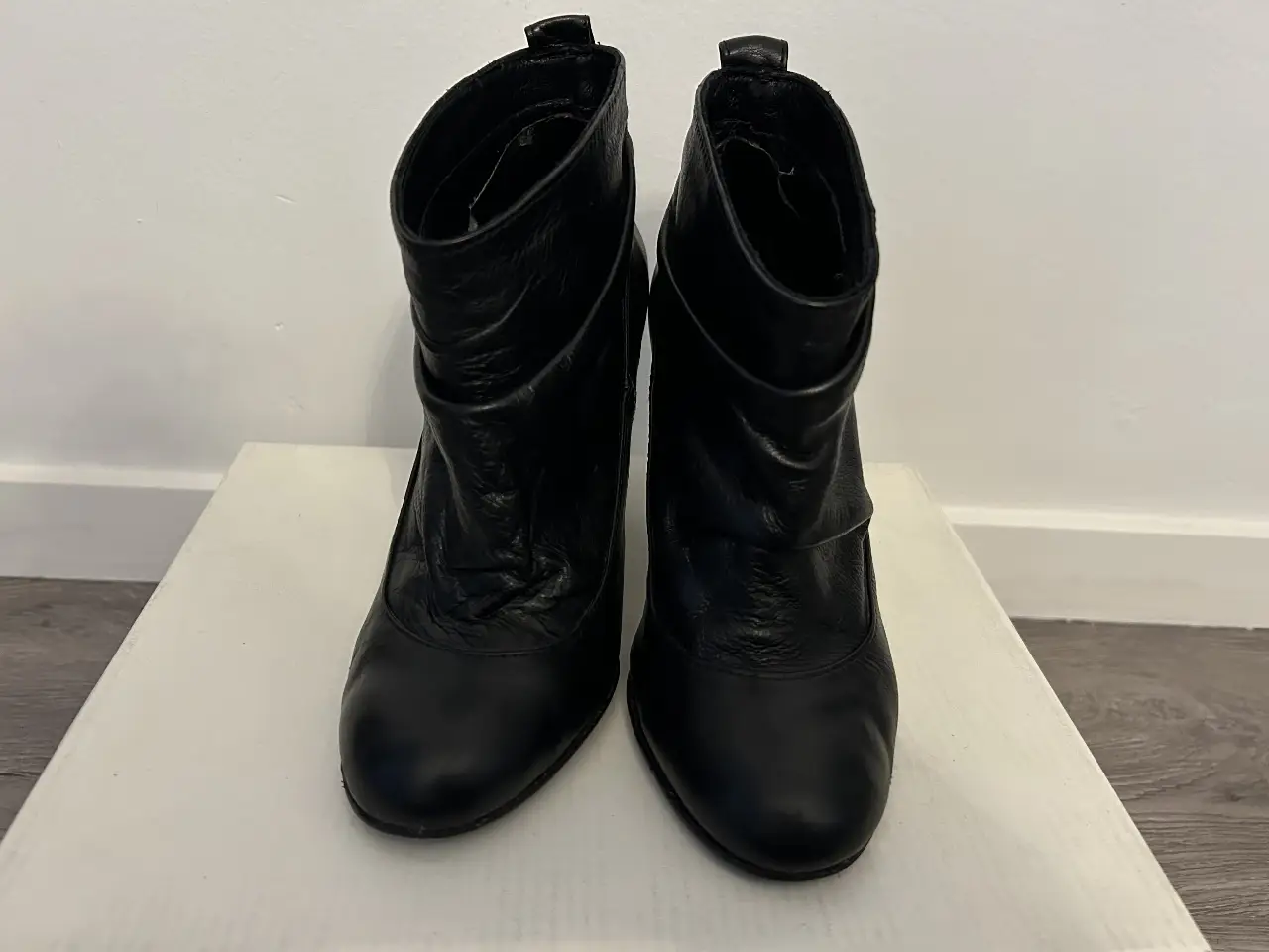 Botines negros de cuero con taco alto y diseño fruncido en la caña. Ideales para un look elegante y sofisticado.