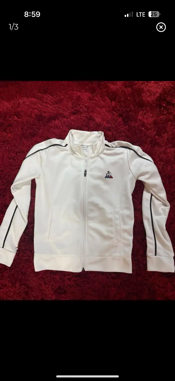 Campera deportiva blanca con detalles en negro. Tiene cierre frontal y el logo de la marca en el pecho. Ideal para un look casual y deportivo.