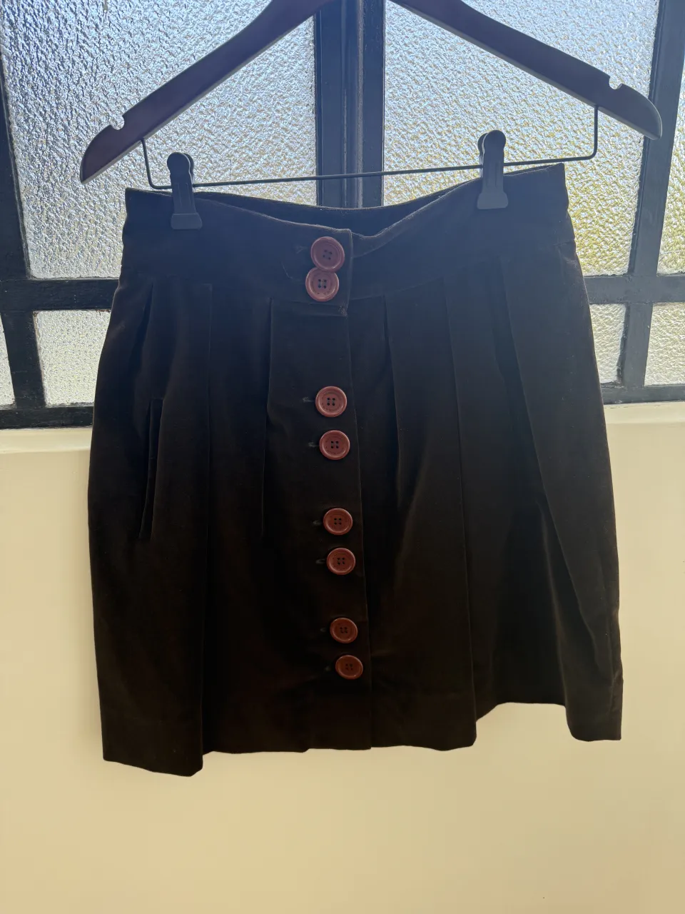 Pollera marrón de pana con botones al frente. Diseño con pinzas y bolsillos laterales. Ideal para un look casual o elegante.