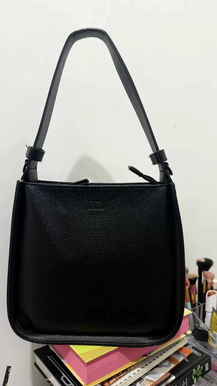 Cartera negra de hombro, con diseño minimalista y elegante. Ideal para llevar tus esenciales con estilo. Confeccionada en material resistente y duradero, perfecta para cualquier ocasión. Muy espaciosa, tiene pequeño detalle en reverso, tiene correa larga 