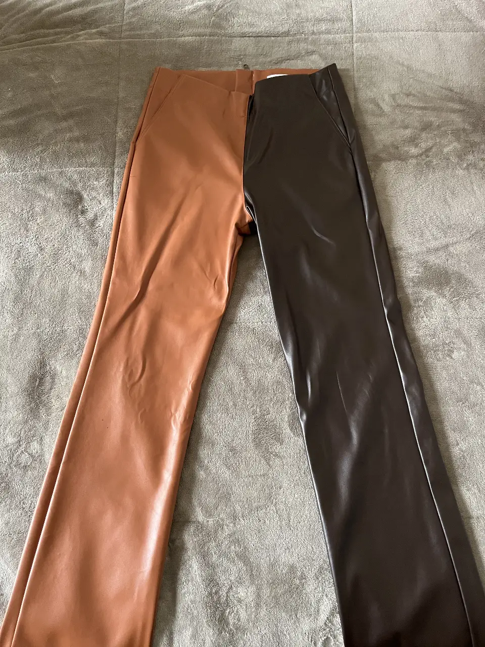Pantalón de cuero sintético bicolor, con un diseño moderno y audaz. Un lado es marrón oscuro y el otro marrón claro, con cierre al detrás. Ideal para un look de impacto.