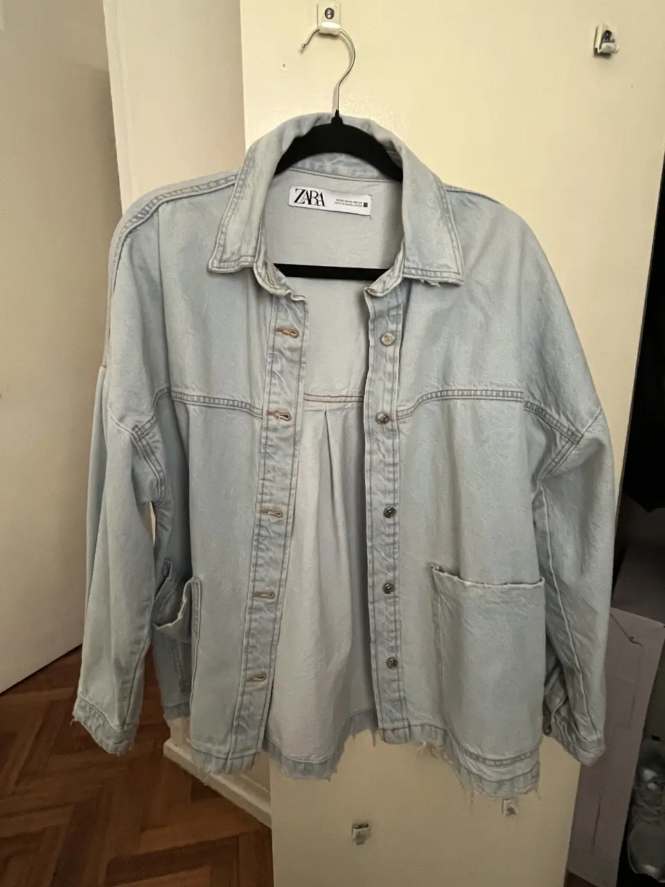 Campera de jean celeste de la marca Zara, estilo oversize, con bolsillos delanteros y botones. 