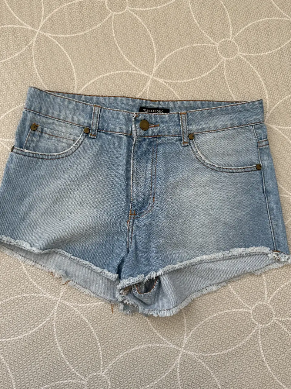 Short de jean celeste de mujer, tiro medio, con detalles de desgaste y flecos en el borde inferior. Ideal para un look casual y fresco. BILLABONG