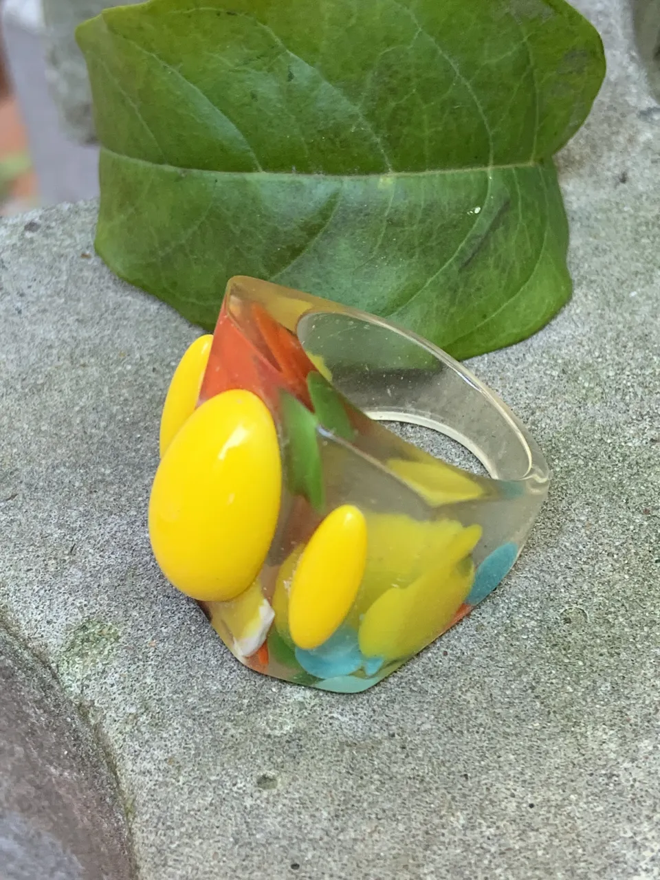 Anillo de resina transparente con detalles en amarillo, rojo, verde y celeste. Diseño moderno y llamativo, ideal para darle un toque de color a cualquier look. 2 cm