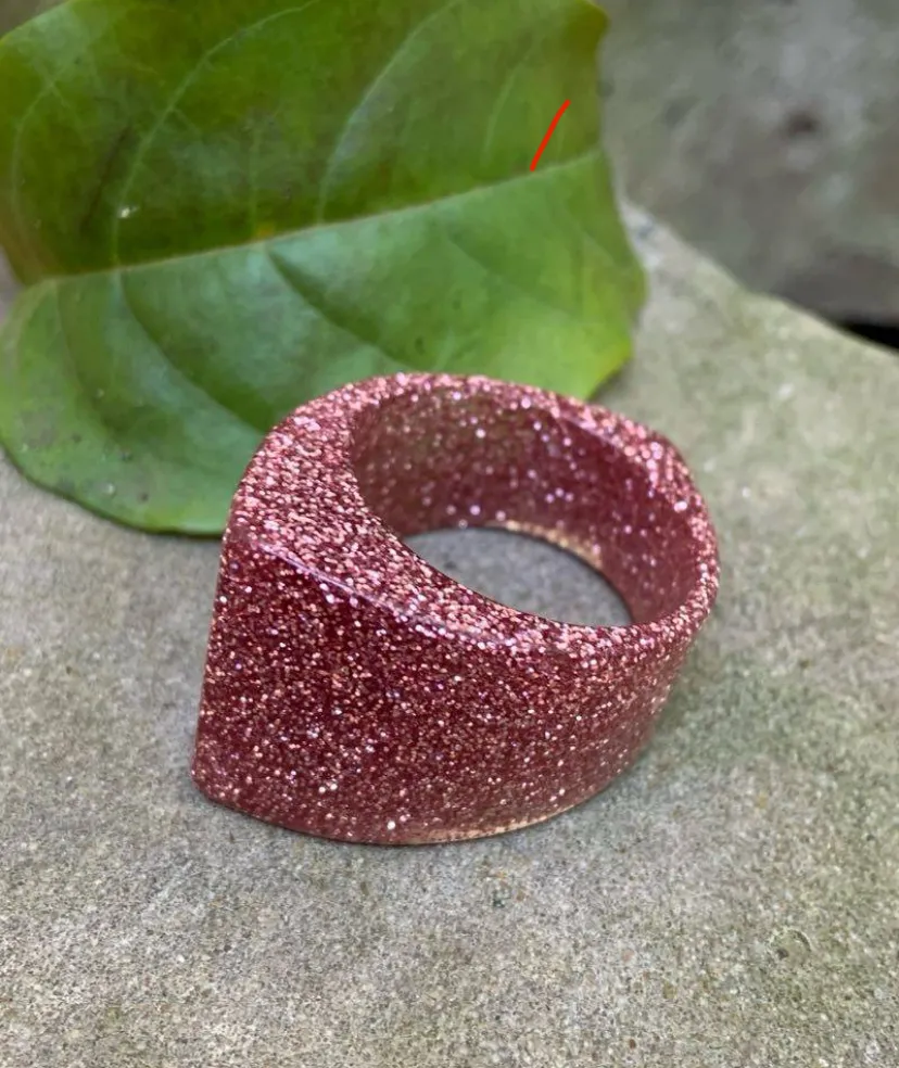 Anillo de resina con glitter rosa, ideal para un look moderno y llamativo. Perfecto para agregar un toque de brillo a cualquier atuendo. 2 cm int 
