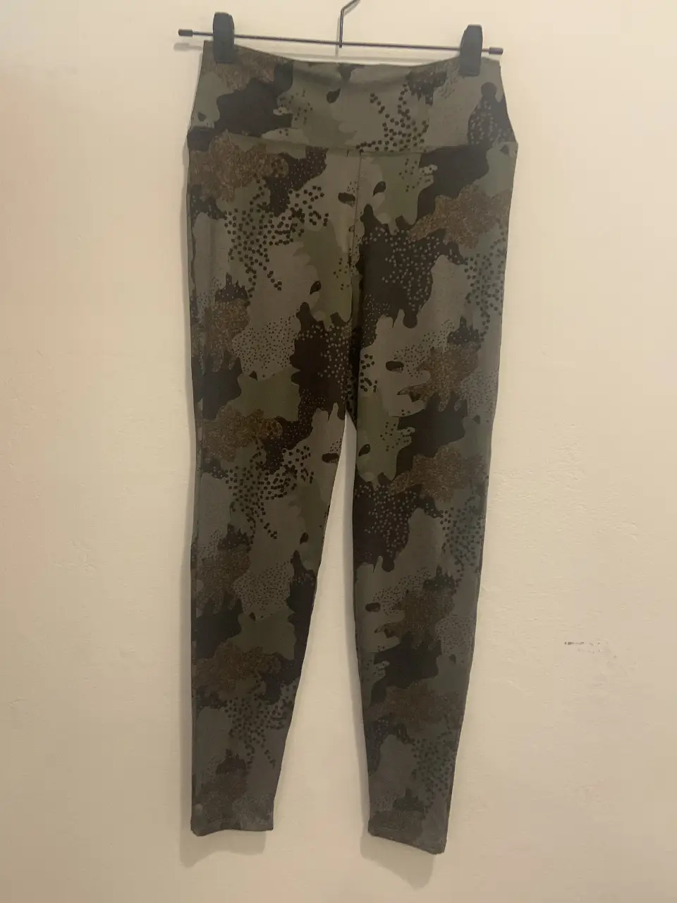 Calzas deportivas de mujer con estampado camuflado en tonos verdes y marrones. Ideales para actividades al aire libre o para un look casual y cómodo.