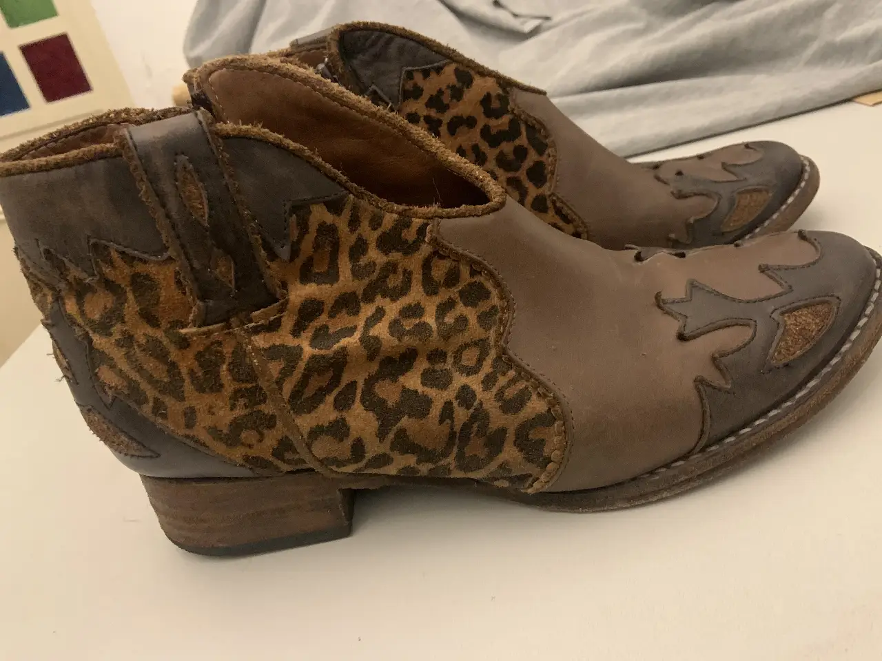 texanas de cuero marrón con detalles de estampado de leopardo en los laterales. Diseño de estilo cowboy con cierre lateral y tacón bajo.