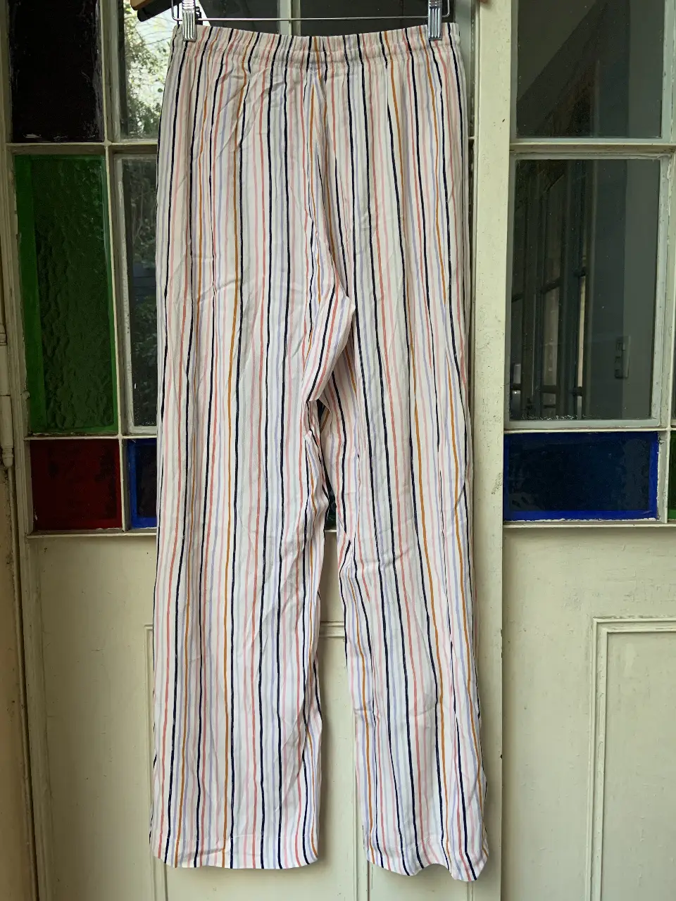Pantalón suelto de mujer con estampado a rayas verticales en tonos rosa, negro, naranja y celeste. Talle 46. Confeccionado en 100% viscosa, ideal para un look casual y fresco.