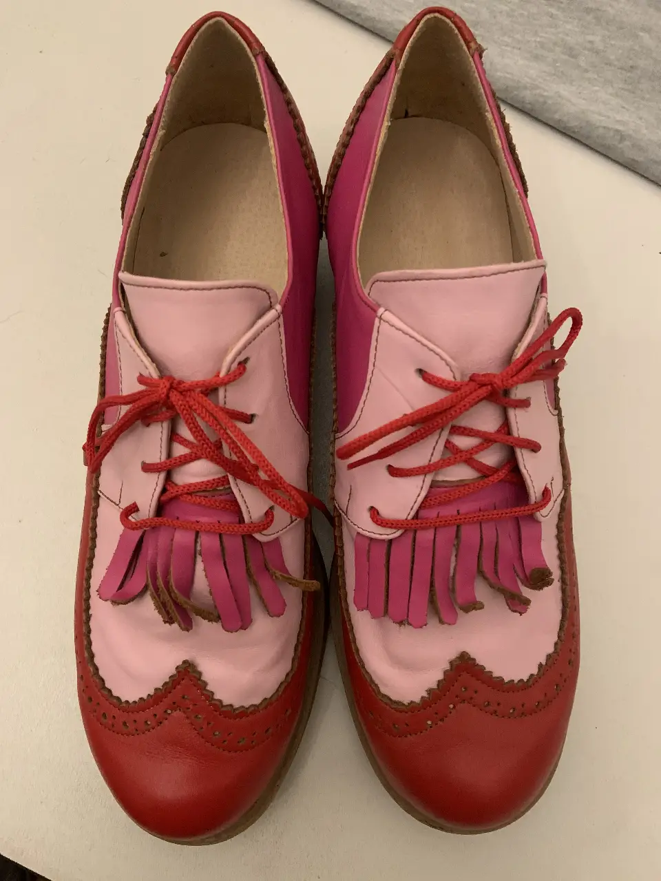Zapatos Oxford de cuero en tonos rosa y rojo, con detalles de flecos y diseño brogue. Ideales para un look retro y con estilo.