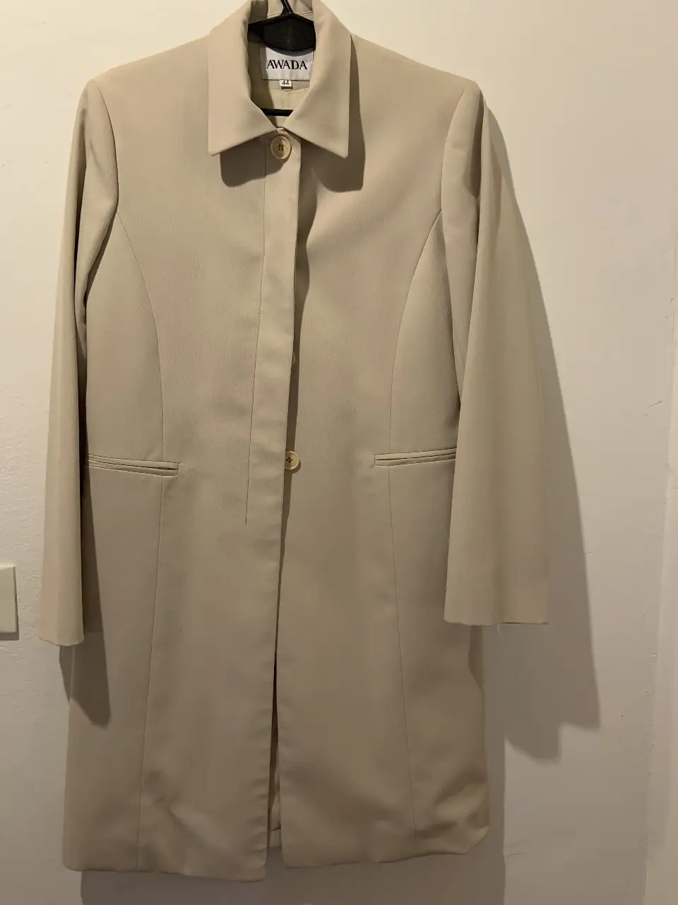 Elegante blazer largo color crudo de la marca Awada, ideal para un look formal o de trabajo. Confeccionado con un tejido de calidad, este blazer presenta un diseño clásico con un solo botón y bolsillos delanteros. Perfecto para combinar con pantalones sastreros o faldas.