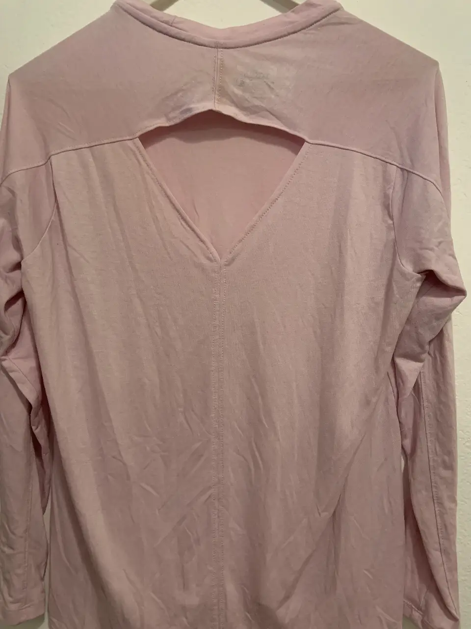 Remera manga larga de color rosa claro, con un diseño moderno y detalles únicos. Cuenta con una abertura en la espalda que le da un toque especial. Ideal para un look casual y cómodo.