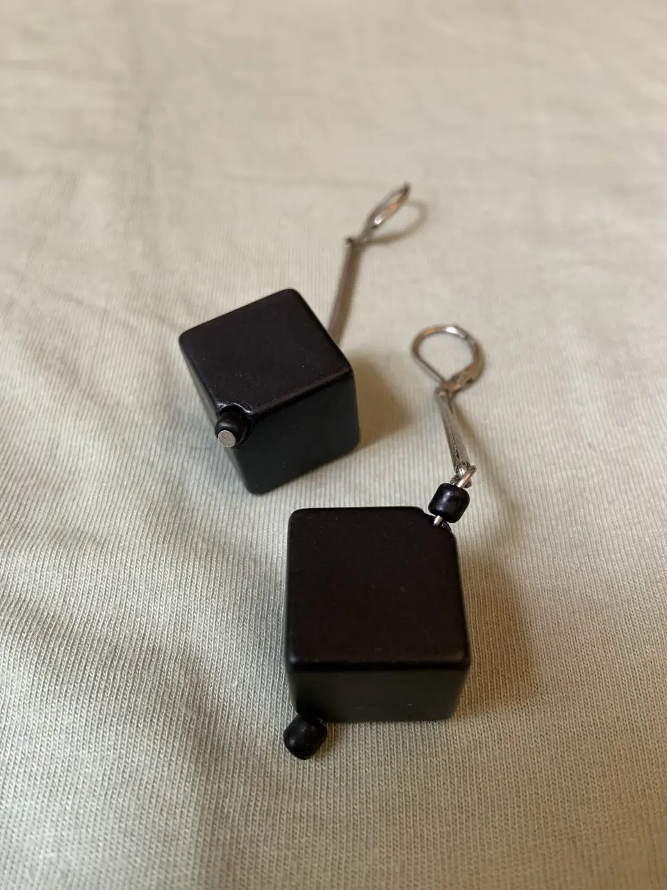 Aros cuadrados colgantes de color negro con detalles plateados. Un accesorio moderno y minimalista para complementar cualquier look.