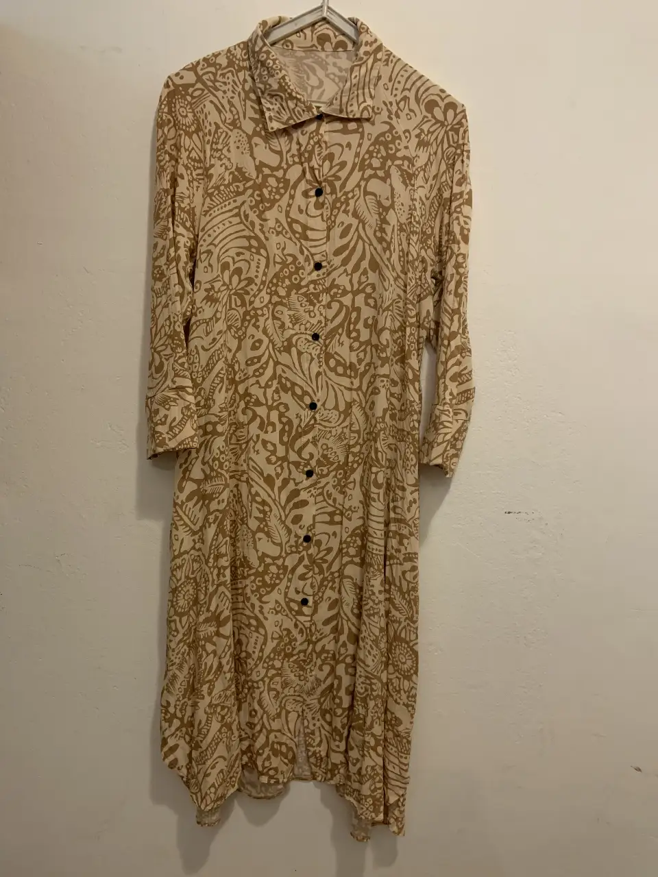 Vestido camisero midi con estampado floral en tonos crudos y marrones. Diseño con botones frontales y mangas 3/4. Ideal para un look casual y cómodo.