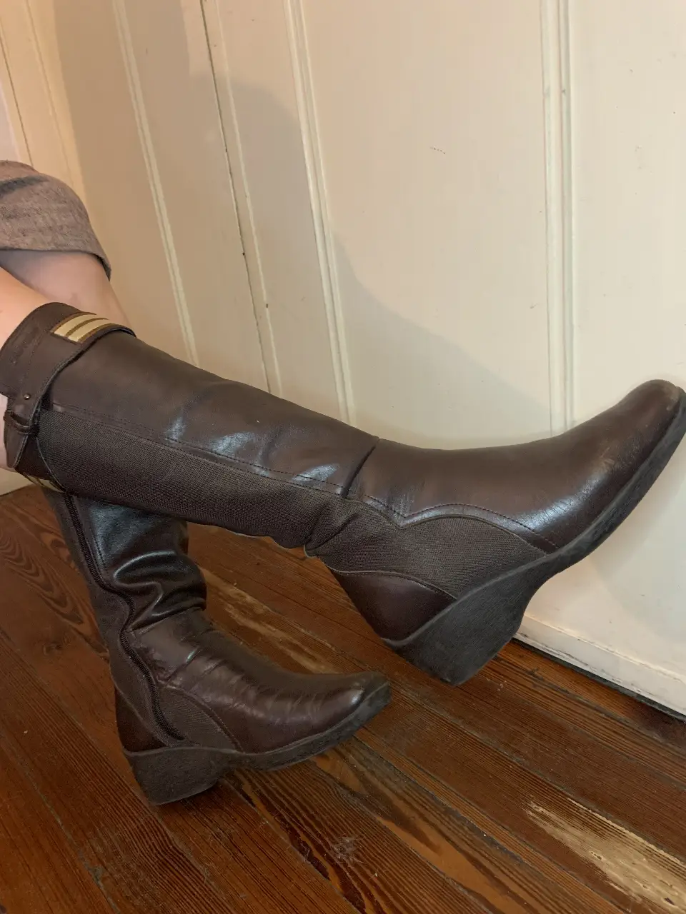 Botas de caña alta de cuero marrón oscuro, con detalle de cinta en la parte superior. Diseño elegante con tacón bajo y cierre lateral para un ajuste perfecto. Ideales para un look sofisticado y abrigado en invierno.