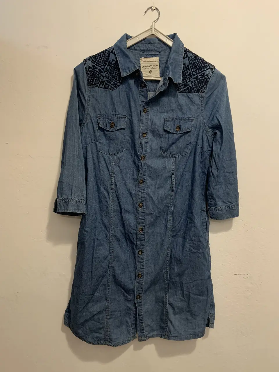 vestido camisero de jean azul con detalles bordados en los hombros y espalda. Corte entallado, con botones y mangas 3/4. Ideal para un look casual y canchero.