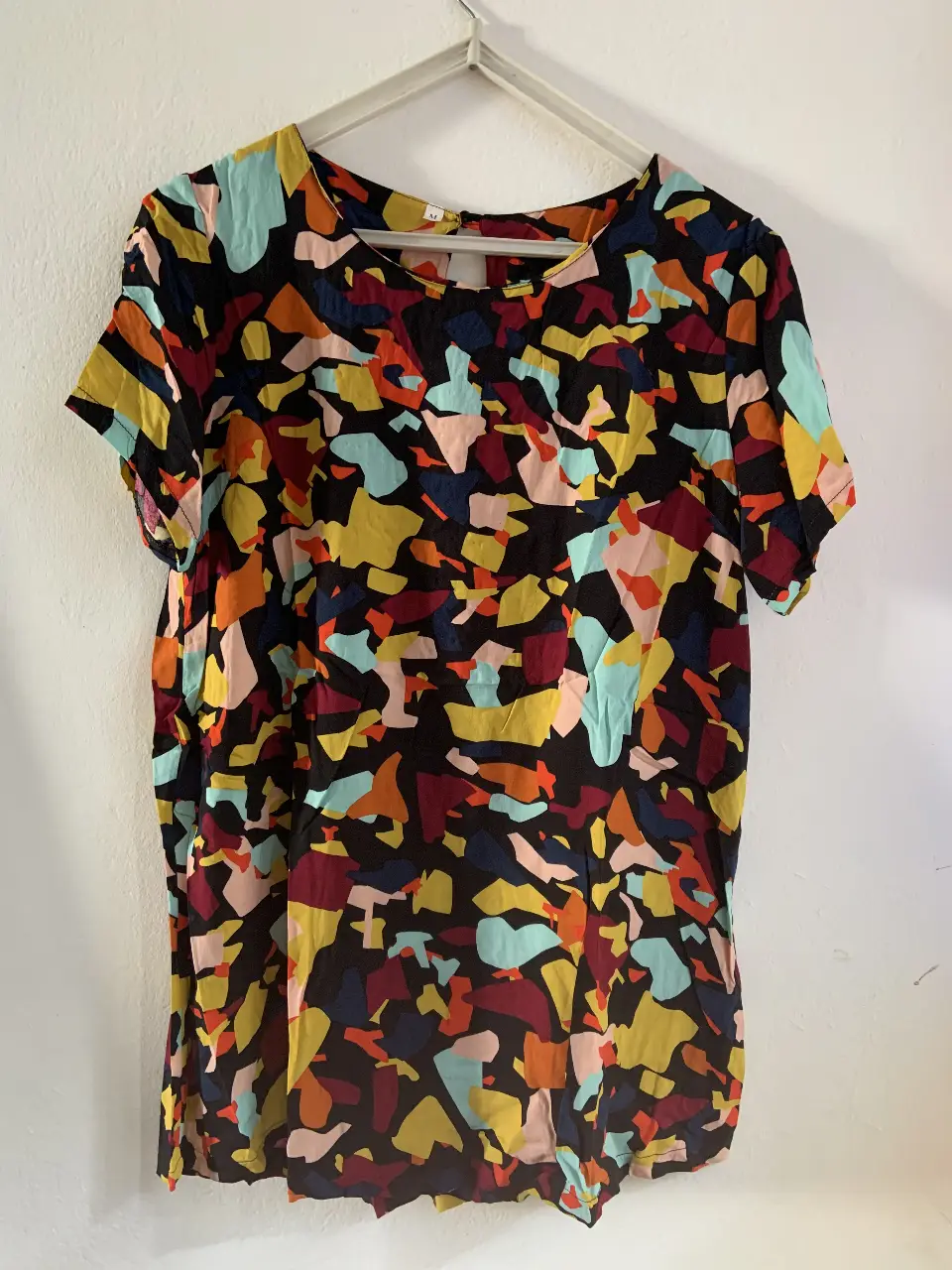 Blusa estampada con diseño abstracto en tonos vibrantes. Corte holgado y cuello redondo con abertura en la espalda. Ideal para un look casual y moderno.