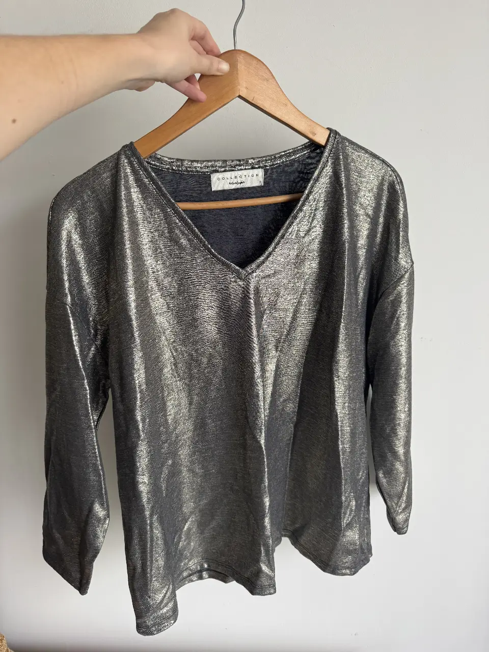 Blusa de mujer con cuello en V y manga 3/4, con un acabado metalizado en tonos grises y plateados. Ideal para un look elegante y moderno.