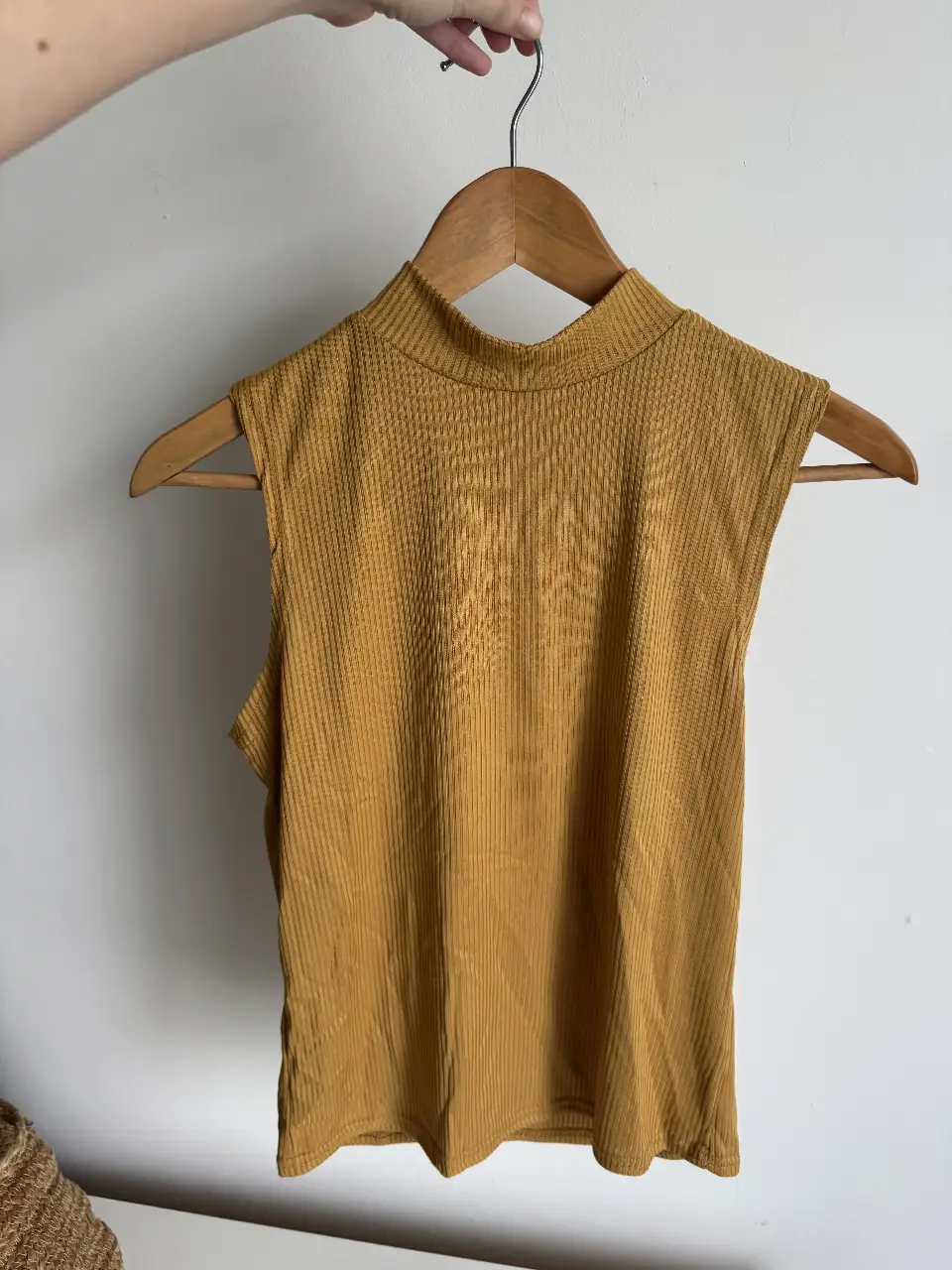 Top sin mangas de cuello alto en color mostaza, ideal para un look moderno y versátil. Perfecto para combinar con jeans o faldas.