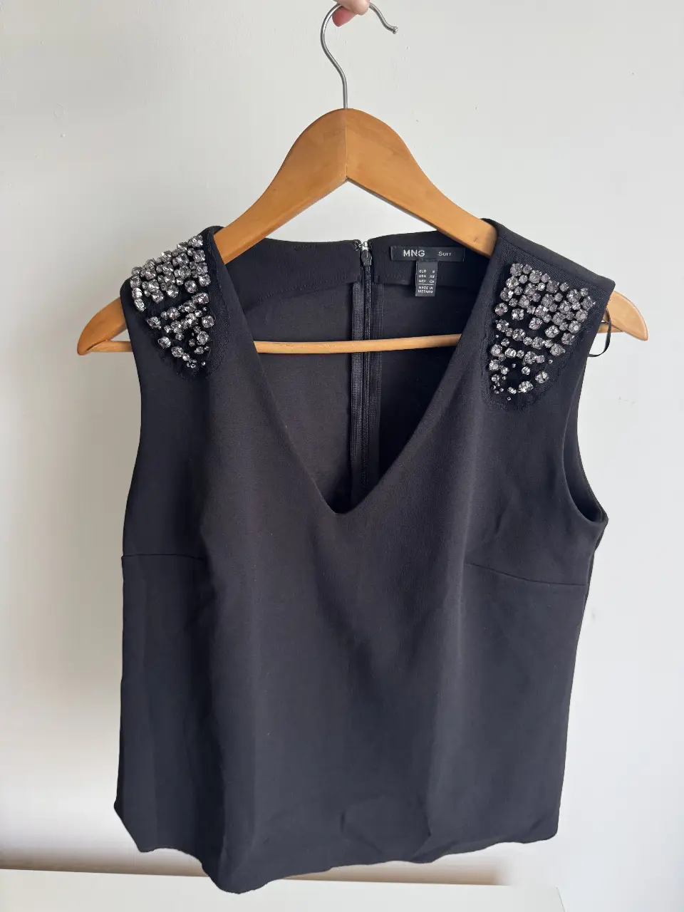 Top negro de mujer con detalles de pedrería en los hombros. Cuello en V y cierre en la espalda. Ideal para eventos formales o salidas nocturnas. El ruedo de adelante está descocido (ver última foto)