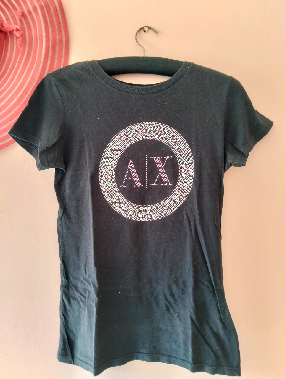 Remera negra de mujer con estampado de la marca A|X en el frente. Diseño con apliques brillantes en forma circular. Ideal para un look casual y moderno.
