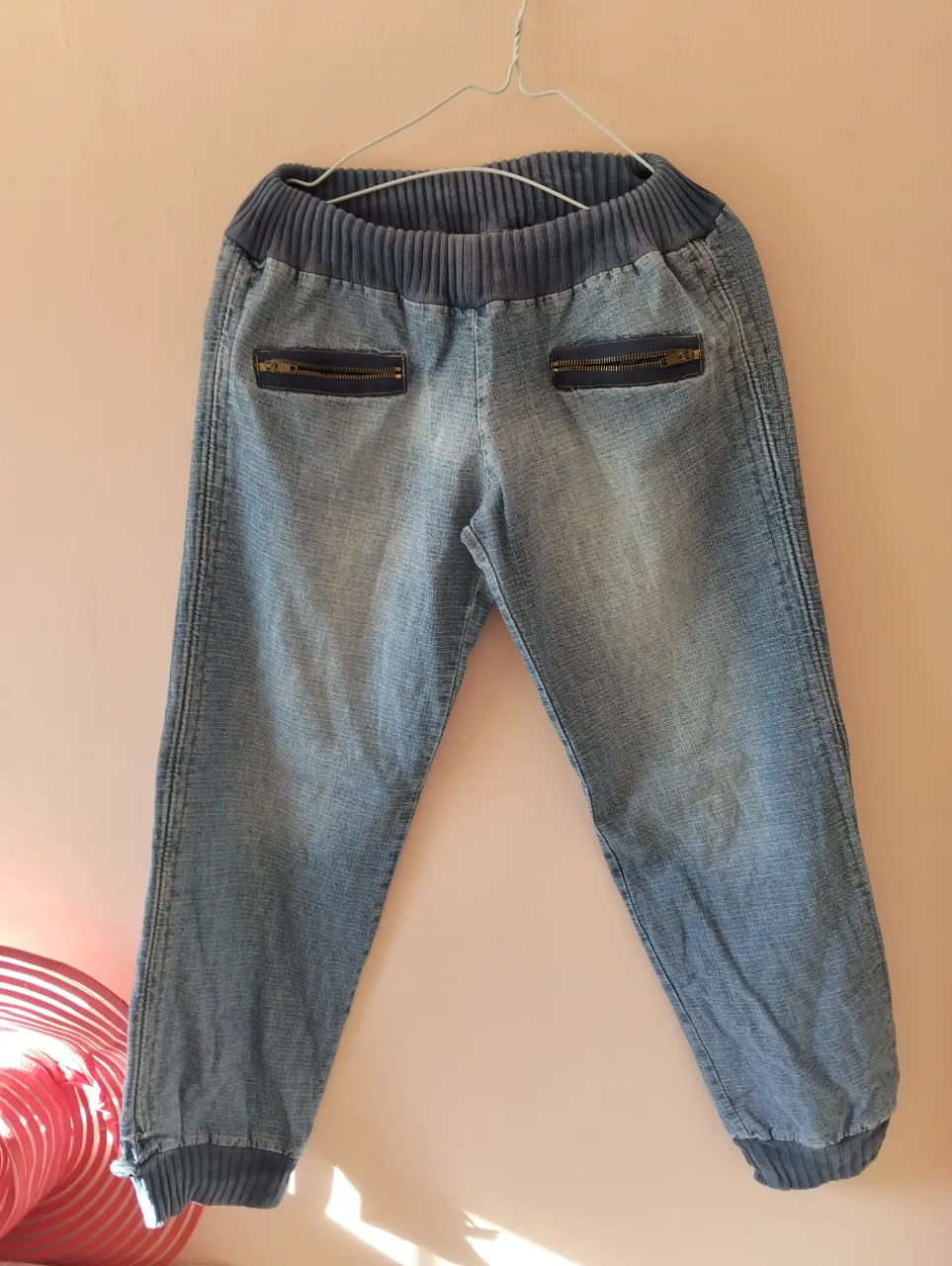Pantalón de jean azul, estilo babucha con cintura elastizada y bolsillos con cierre. Ideal para un look casual y cómodo.
