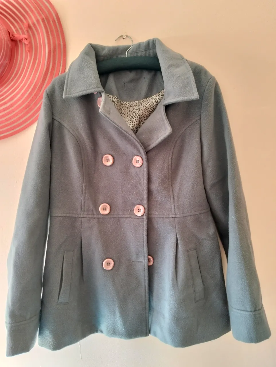 Tapado gris de paño con botones rosas. Posee forro interior con estampado animal print. Ideal para el invierno.