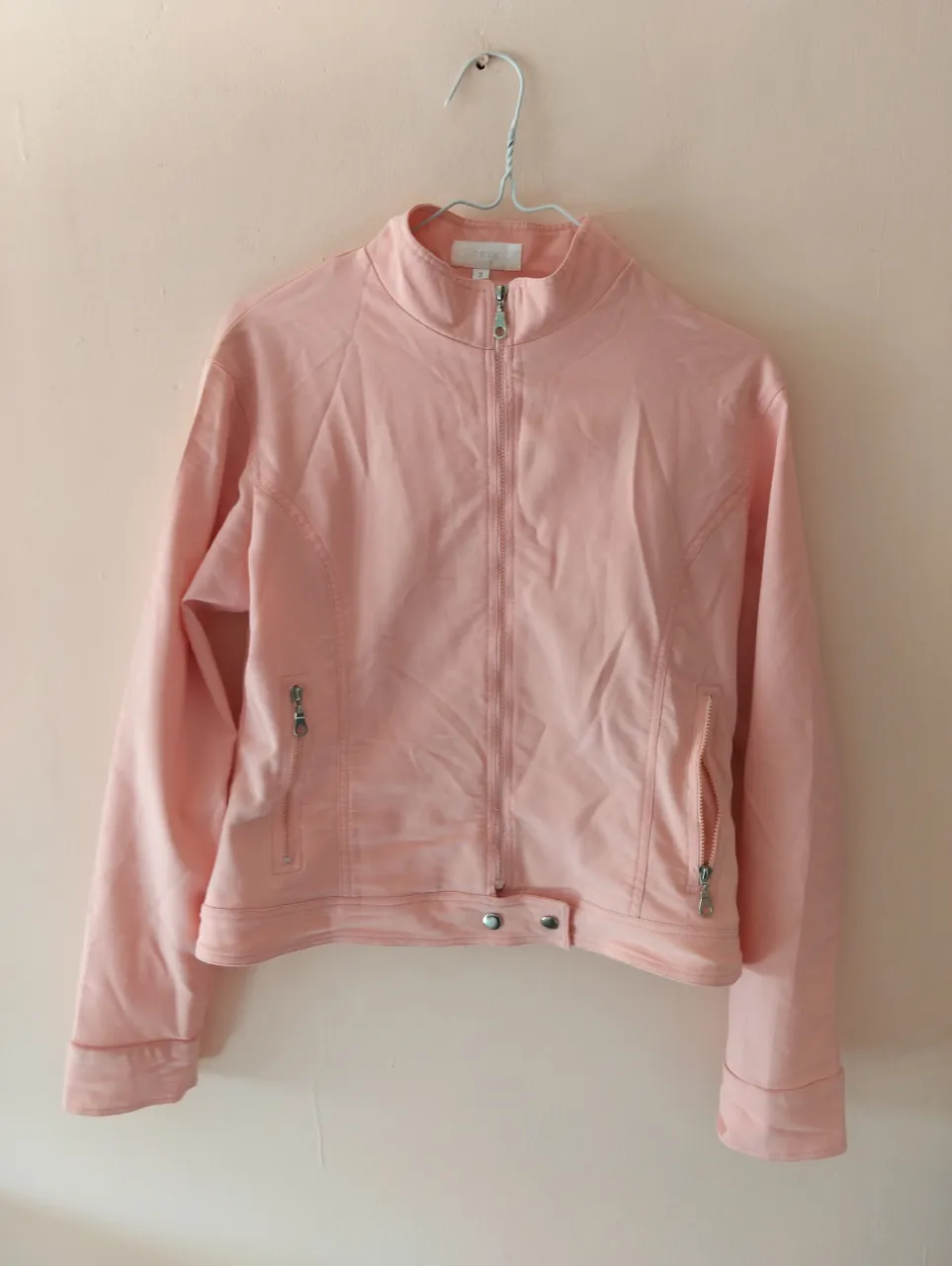 Conjunto de campera y pantalón rosa, ideal para un look casual y cómodo. La campera tiene cierre y bolsillos, mientras que el pantalón presenta detalles de diseño y bolsillos con cierre. Perfecto para un estilo moderno y versátil.