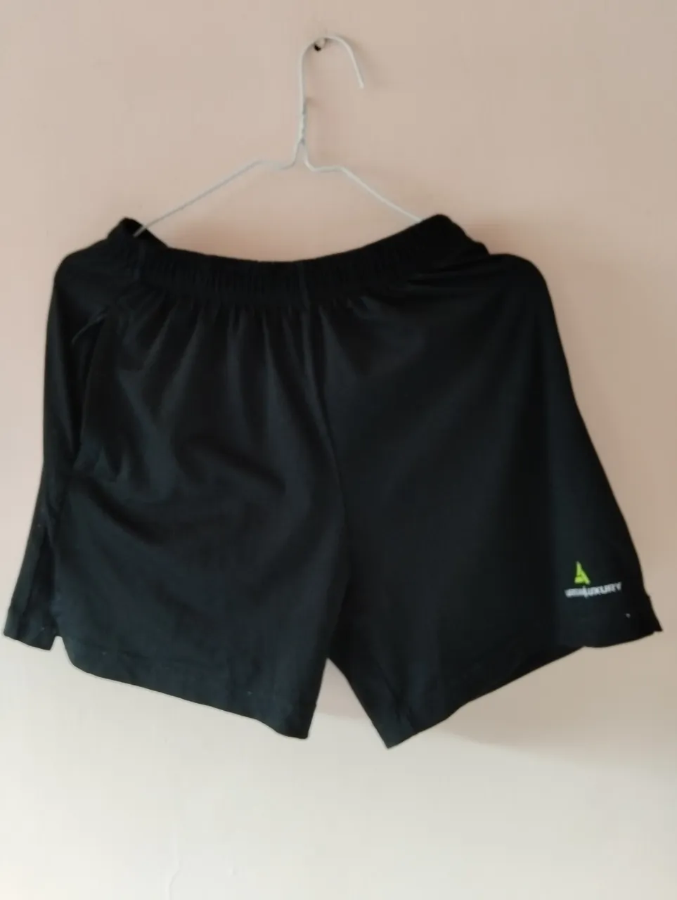 Short deportivo negro para hombre, ideal para actividades físicas. Cuenta con un bolsillo con cierre y el logo de la marca Urban Luxury en verde.