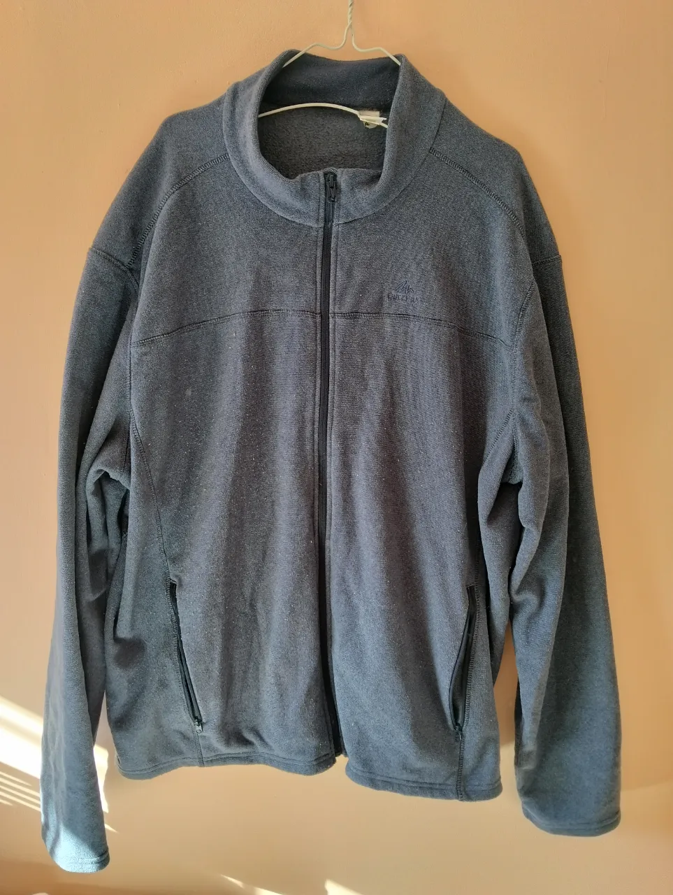 Buzo con cierre de hombre, color gris, de la marca Quechua. Ideal para actividades al aire libre o uso diario. Confeccionado en polar, ofrece abrigo y comodidad.
