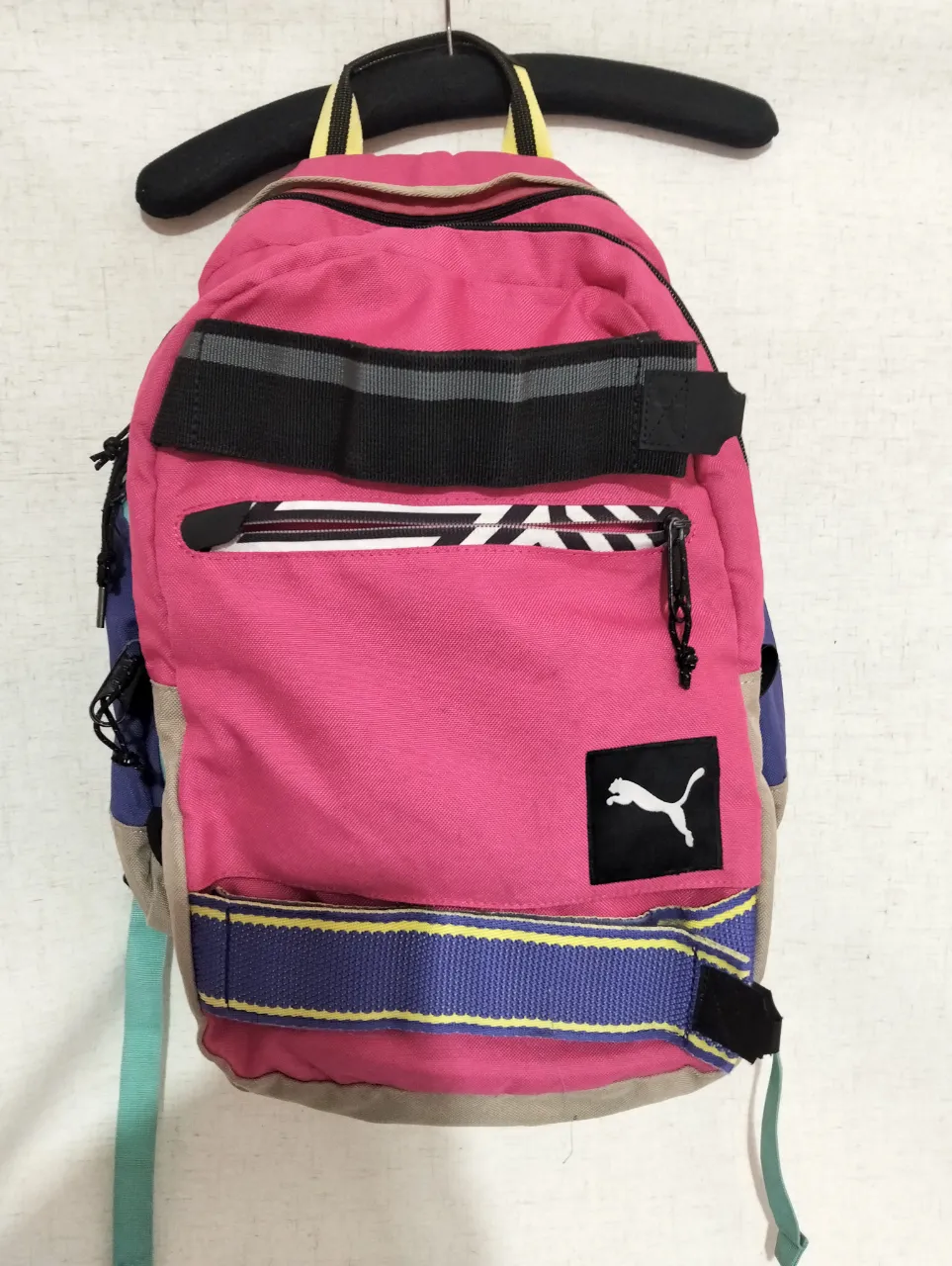 Mochila Puma rosa con detalles en azul, negro y amarillo. Ideal para llevar tus cosas con estilo y comodidad. Perfecta para el día a día.