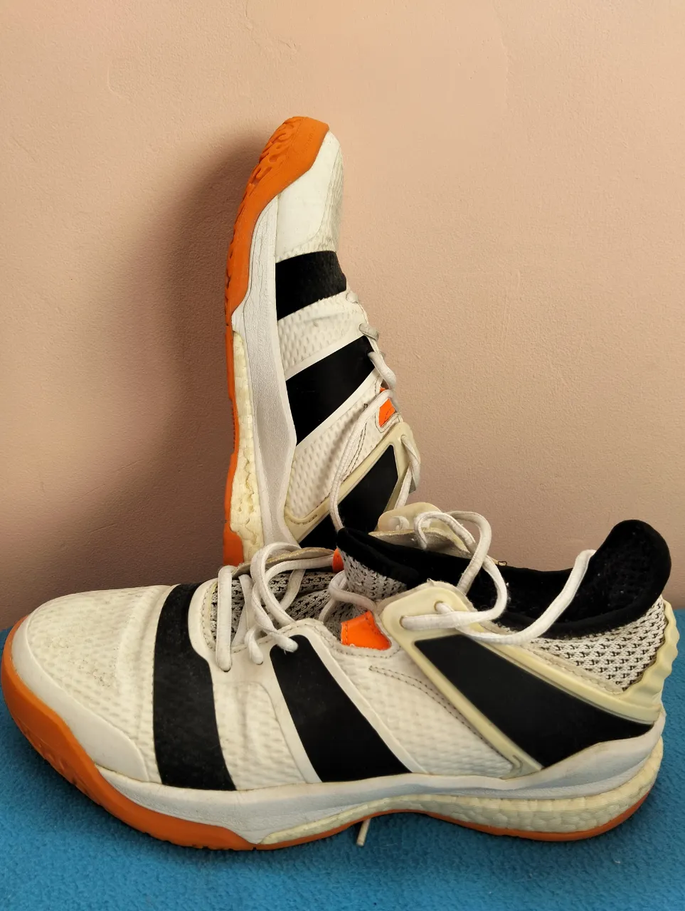 Zapatillas deportivas blancas con detalles en negro y naranja. Ideales para running o entrenamiento en gimnasio. Diseño moderno y cómodo.