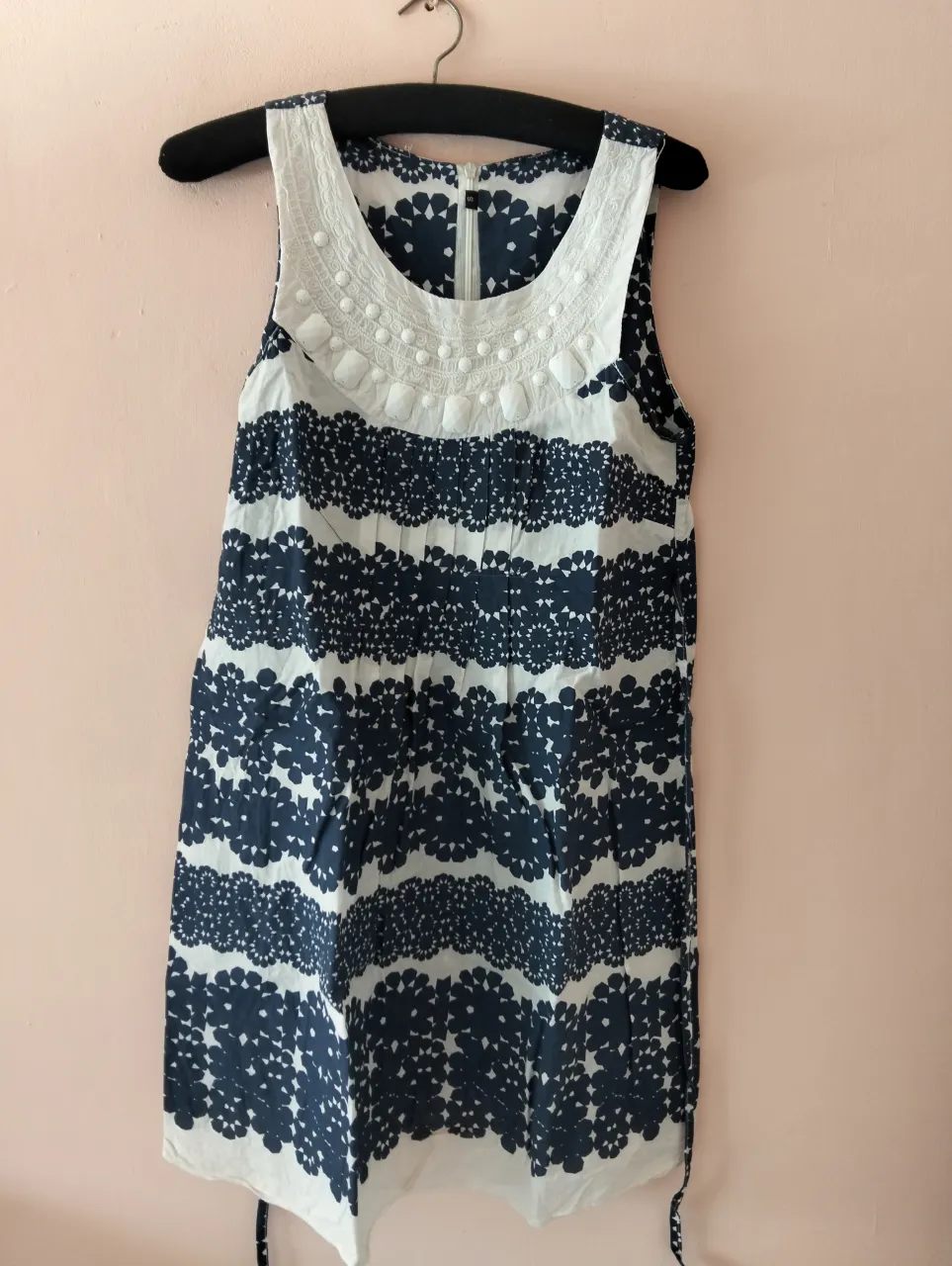 Vestido mini de mujer, sin mangas, con estampado floral en azul y blanco. Cuello redondo con detalles decorativos. Ideal para un look fresco y casual.