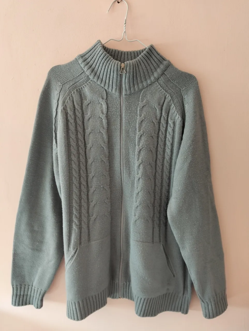 Sweater de hombre con cierre y bolsillos, tejido grueso en color gris. Diseño con detalles trenzados y cuello alto.