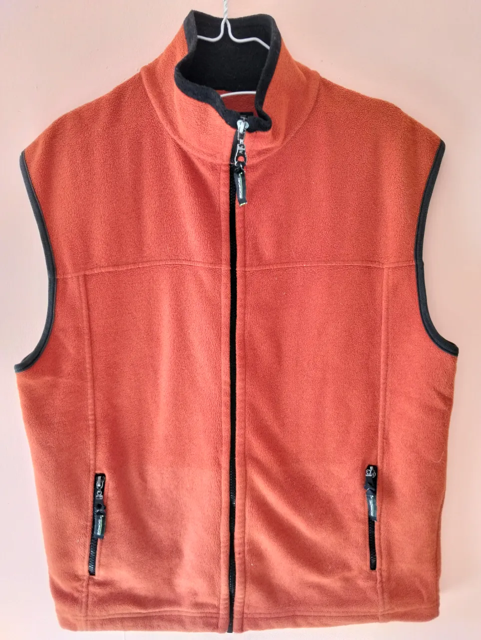 Chaleco polar naranja con detalles en negro. Cuello alto y cierre frontal. Bolsillos con cierre. Ideal para el invierno.