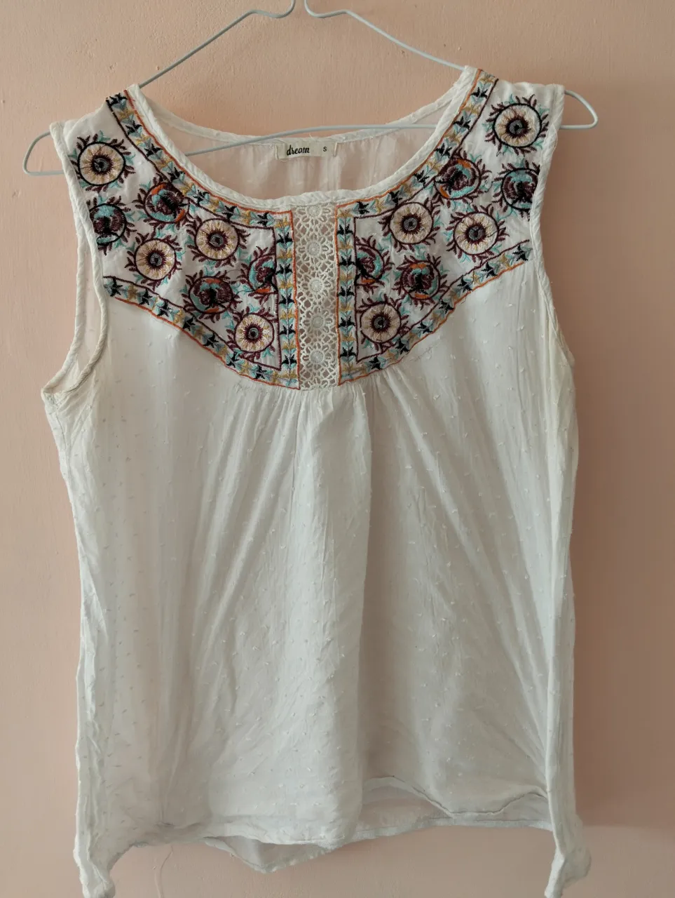 Blusa de mujer sin mangas, blanca con detalles bordados en el cuello. Ideal para un look fresco y casual.