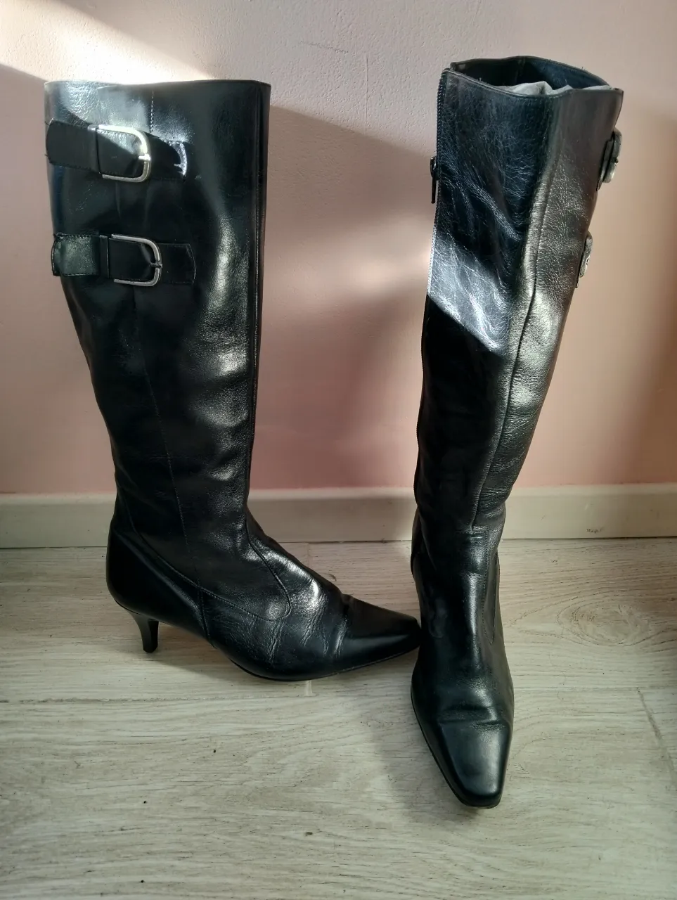 Botas de caña alta de cuero negro, con detalles de hebillas y cierre lateral. Ideales para un look elegante y sofisticado.