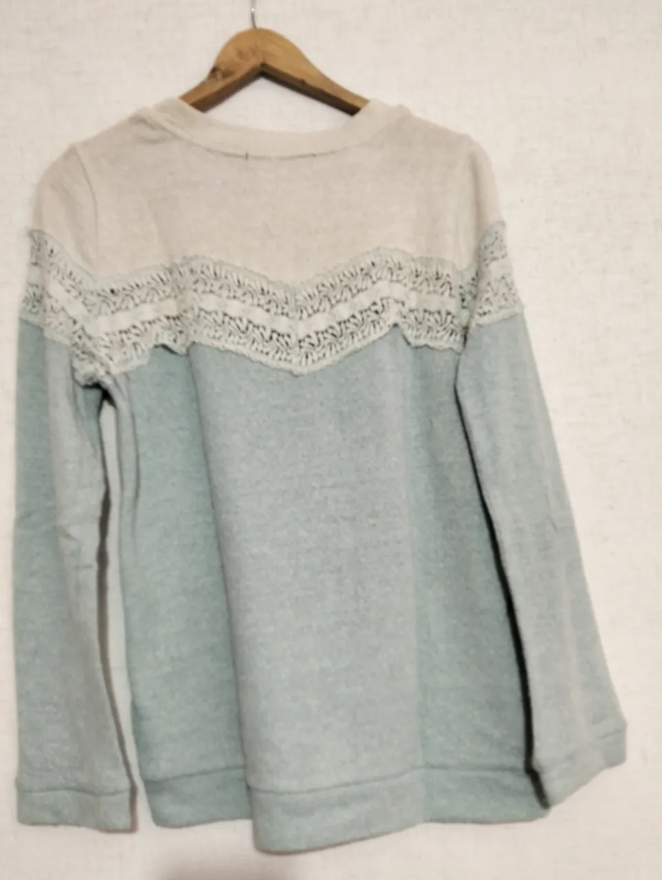 Buzo de cuello redondo para mujer, con detalle de encaje en el pecho. Combina dos tonos, celeste y crudo, ideal para un look casual y cómodo.