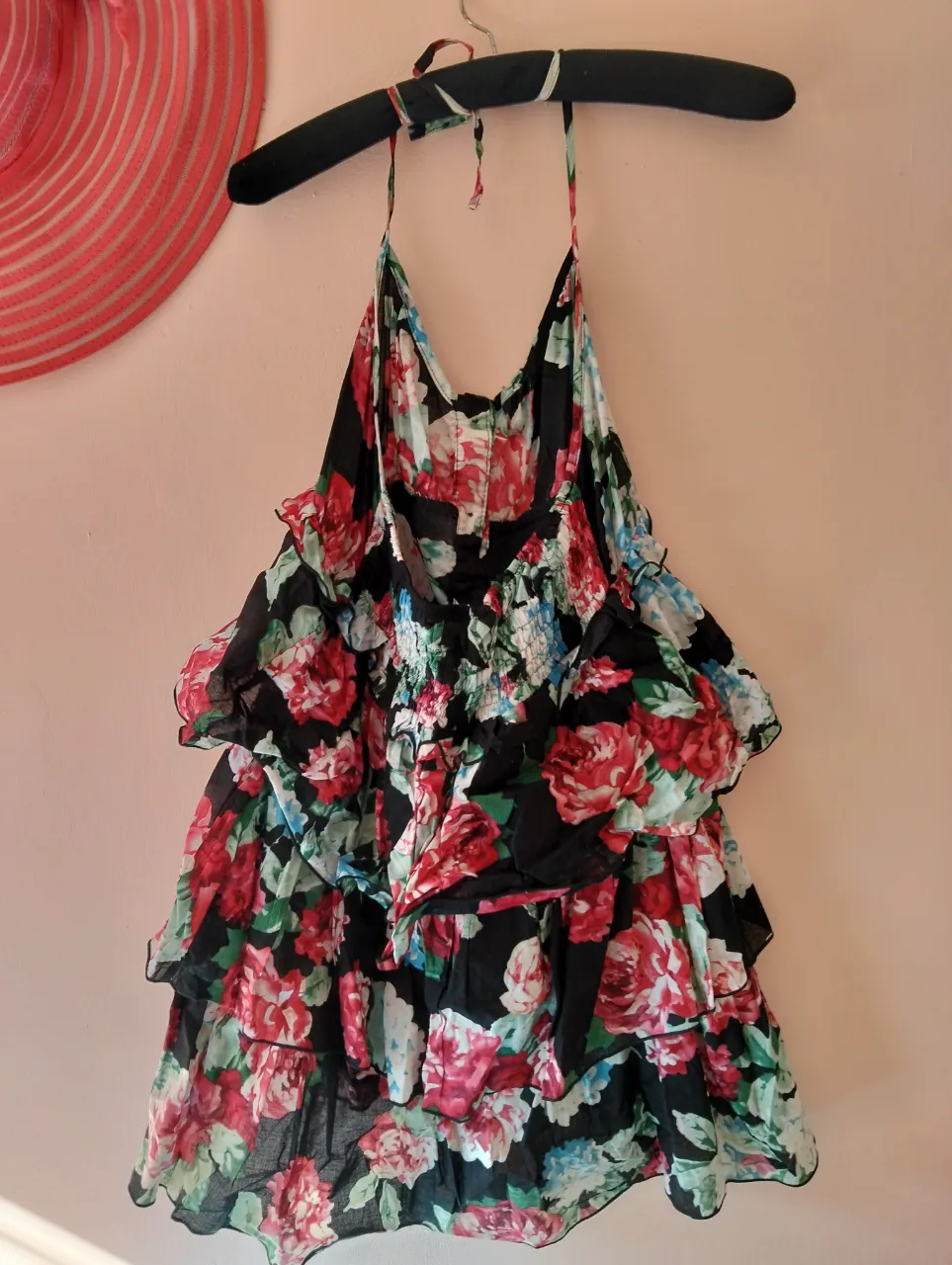 Vestido mini con estampado floral en tonos rojos y negros. Diseño con volados y tirantes finos, ideal para un look fresco y femenino.