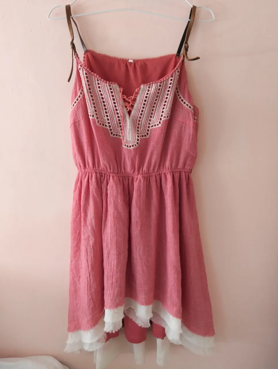 Vestido mini de mujer, color rosa con detalles en blanco. Diseño con tirantes finos y escote en V adornado con encaje. Cintura elastizada y falda con volados.