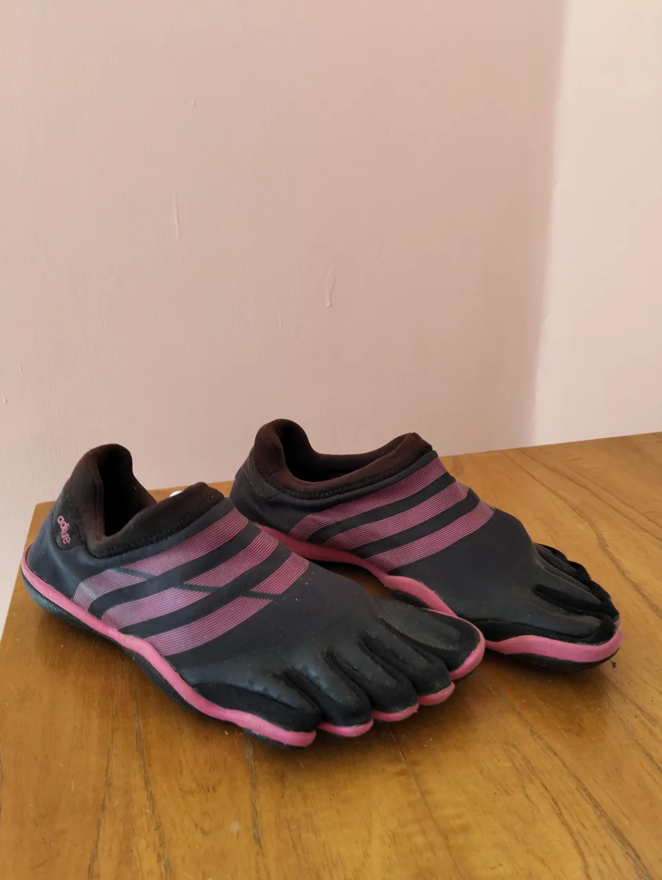 Zapatillas Adidas Five Fingers negras con detalles en rosa, ideales para actividades deportivas de agua y entrenamiento. Diseño innovador con dedos separados para mayor comodidad y agarre.
