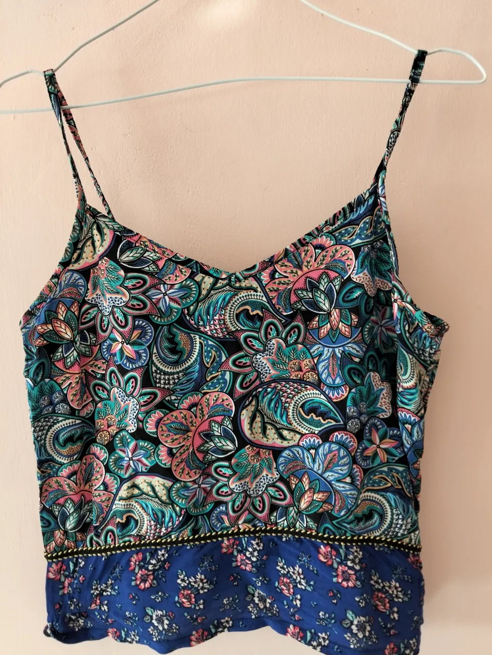 Top de mujer con estampado floral y paisley en tonos vibrantes. Diseño con tirantes finos y detalle de borde en la parte inferior. Ideal para un look fresco y casual.