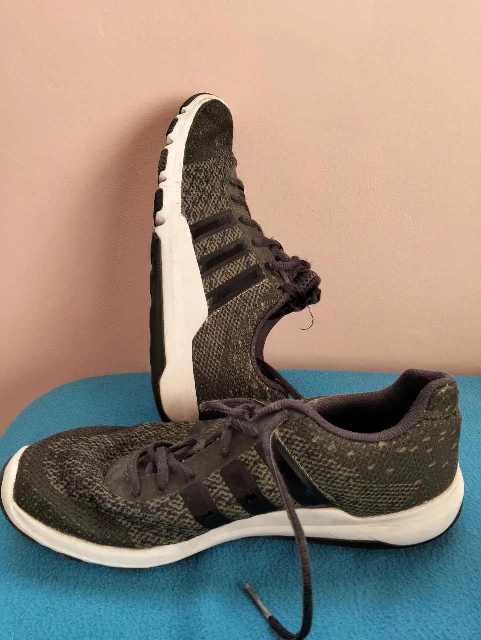Zapatillas Adidas para hombre, de color gris con detalles en negro y suela blanca. Ideales para entrenamientos y uso diario.
