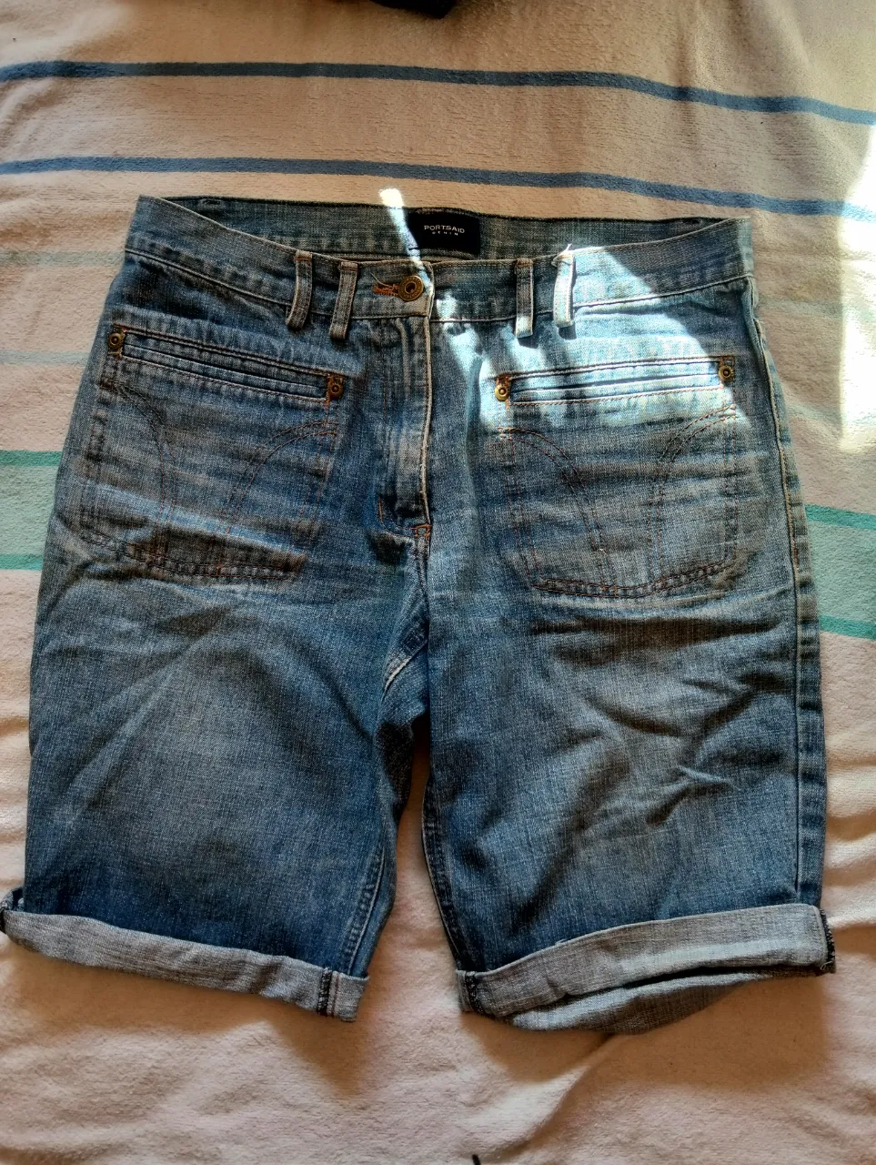 Bermuda de jean azul claro, con bolsillos delanteros y traseros con cierre. Tiro medio y dobladillo en la basta. Ideal para un look casual y cómodo.