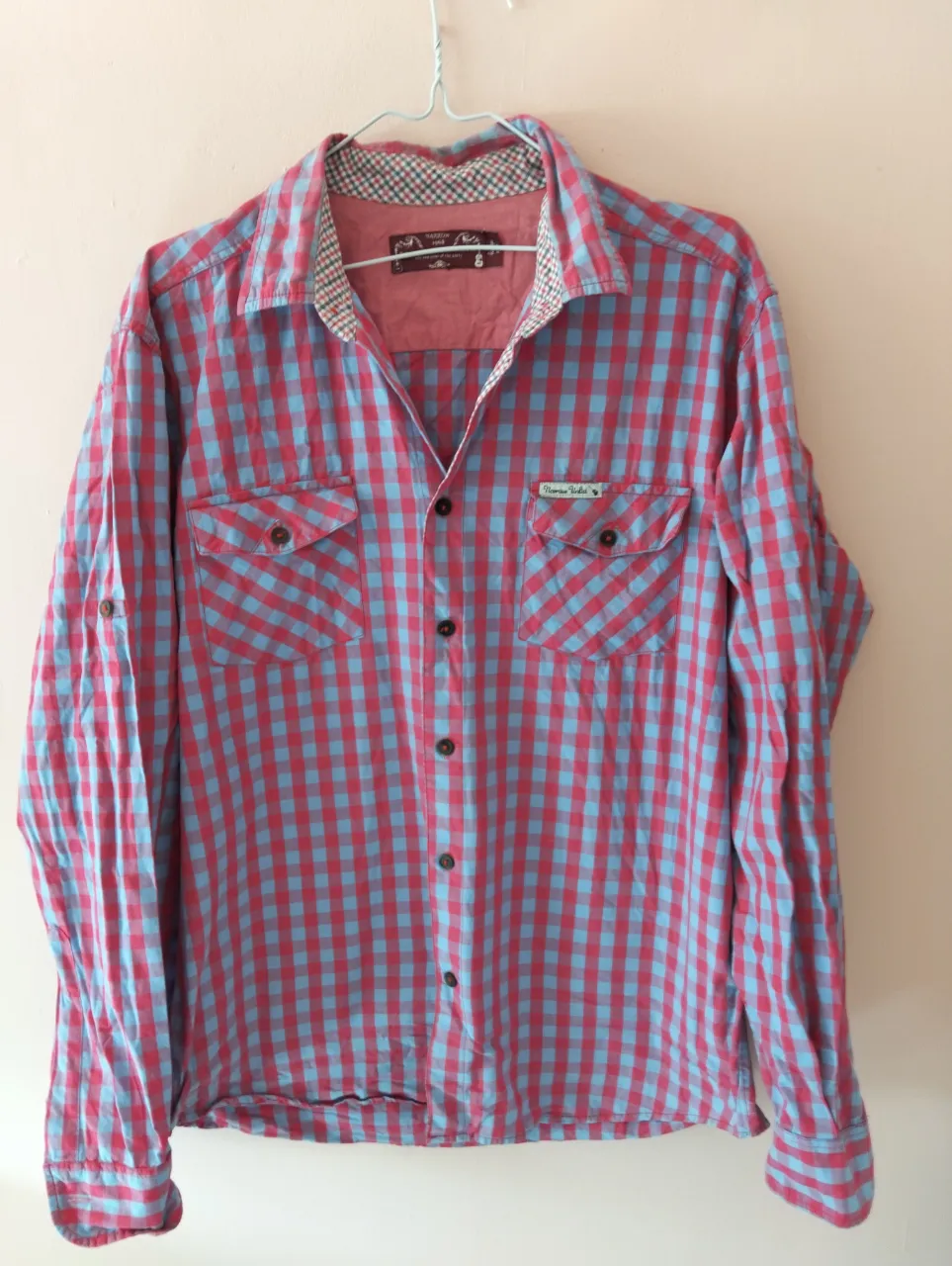 Camisa a cuadros roja y celeste de manga larga, con dos bolsillos delanteros y cuello clásico. Ideal para un look casual y moderno.